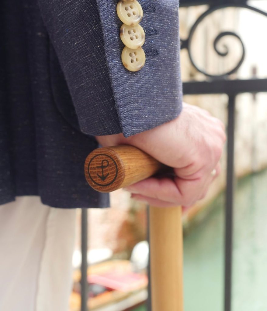 Mano che impugna un bastone da passeggio in legno di briccola con logo Pieces of Venice